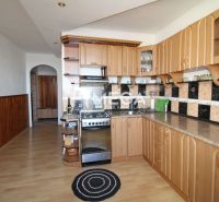 The kitchen in a 3-room apartment with a wooden decor floor and a curved cabinet.
