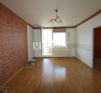 A room in a 3-room apartment with a wooden decor floor and brick wallpaper.