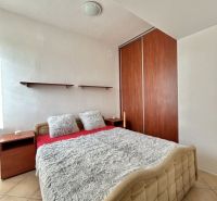 A bedroom with a double bed, pillows, and a built-in wardrobe in a two-room apartment.