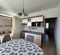 A kitchen in a 2-room apartment with a dining table and entrance to the bedroom.