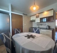 A kitchen in a 2-room apartment with a dining table and lighting.