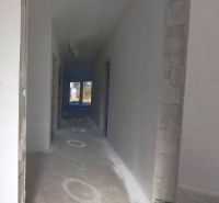 A hallway in a family house with an unfinished floor and bare walls.