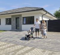 A family house in Hôrka nad Váhom with a family on a paved driveway.