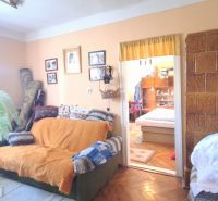 A room in a family house with a sofa, decorations, and wooden decor on the floor.
