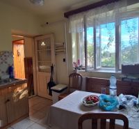 A kitchen in a family house with a window, wooden furniture, and equipment on the table.