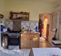 A kitchen in a family house with wooden furniture, a refrigerator, and an electric stove.