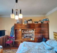 A room in a family house with furniture, a bed, and a television, simple interior.