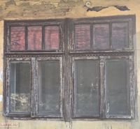 Peeling plaster and an old wooden window on a family house in Hejce.