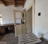 Interior of a family house with a massive table and a rustic wooden ceiling.