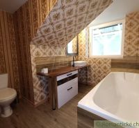 A bathroom in a family house with wallpaper and a wooden decor floor.