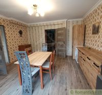 Dining room in a family house with patterned wallpaper and wooden decor flooring.