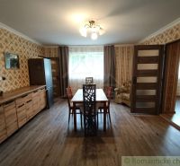 A dining room in a family house with wallpaper and a wooden decor floor.