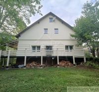 A family house in Staškov, surrounded by greenery, with wood stored under the terrace.