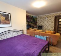 A bedroom in a family house with a purple blanket, a sofa, and a fireplace.