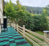 The terrace of the family house in Staškov leads to a landscaped garden with lush vegetation.