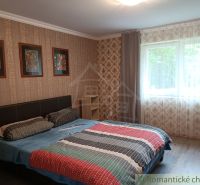 Bedroom in a family house with a double bed, window, and decorative wallpapers.