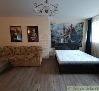 A room in a family house with a bed, a sofa, and pictures on the wall.