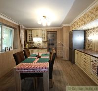 A kitchen in a family house with patterned wallpaper and a wooden decor floor.