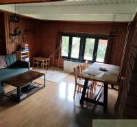 Living room in a cottage with wood-patterned flooring and a dining area.