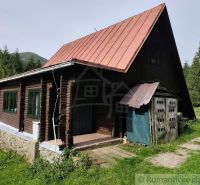 A cottage in Rajecká Lesná with a metal roof and wooden walls surrounded by nature.