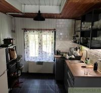 A kitchen in a cottage with a rustic atmosphere and wooden decor on the ceiling.