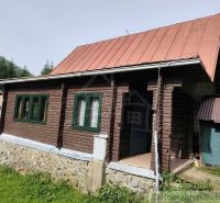 A wooden cottage with a metal roof in the nature of Rajecká Lesná, surrounded by greenery.