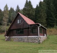A cottage in Rajecká Lesná surrounded by forest, with a stone foundation and a roof.