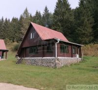 A cottage in Rajecká Lesná with a red roof, forest, and grassy surroundings.