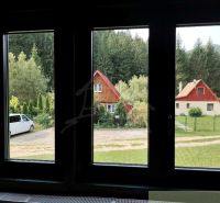 View of cottages in Rajecká Lesná, surrounded by greenery and cars.