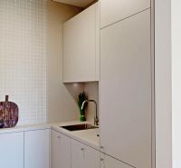 Kitchen area in a 2-room apartment with clean white tiles and a sink.