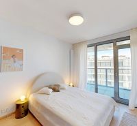 A bright bedroom in a 2-room apartment with a balcony and a wooden decor floor.