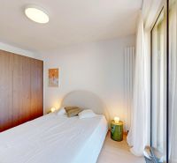 A bedroom with a white bed, a large wardrobe, and a floor with a wooden decor in a two-room apartment.