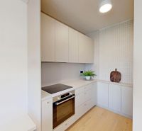 A kitchen in a 2-room apartment with white cabinets and a wood-patterned floor.