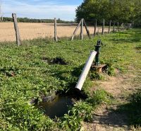 A pump with greenery in the gardens in Kopčany, rural landscape in the background.