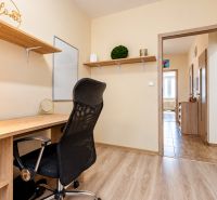 A workspace with a desk and a black office chair, complemented by a floor with a wooden decor.