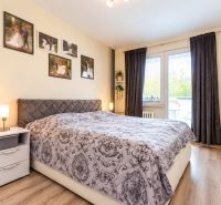 A bedroom with a decorative bed, a nightstand, and curtains in a three-room apartment.