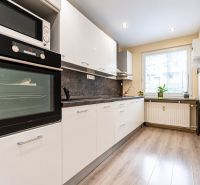 A kitchen in a 3-room apartment with white cabinets and a wood-patterned floor.