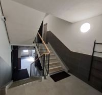 The staircase of an apartment building in a 3-room flat with modern tiles and railing.