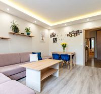 Living room in a 3-room apartment with a sofa, table, and wooden decor flooring.
