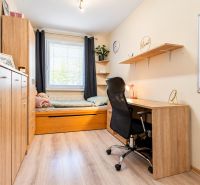 A study with a bed, a desk, and a shelf, a floor with a wooden decor in a 3-room apartment.