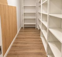Storage space with white shelves and a wooden decor floor in a 2-room apartment.