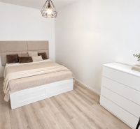 A room in a 2-room apartment with a bed, a dresser, and a floor with a wood decor.