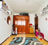 A room in a 3-room apartment with a carpet, toys, and a cabinet with a wood decor.