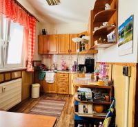 A kitchen in a 3-room apartment, with a wooden decor floor, red curtains, and equipment.