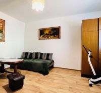 A room in a 3-room apartment with a sofa, a table, and a floor with a wooden decor.
