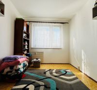 A simple room in a 3-room apartment with a carpet and a shelf by the window.