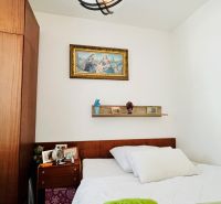A bedroom in a three-room apartment with a picture and a spotlight shelf above the bed.