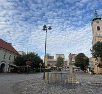 Commercial premises in Topoľčany with a paved square and a church in the background.