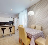 A kitchen in a family house with a kitchen island and a dining table with modern chairs.
