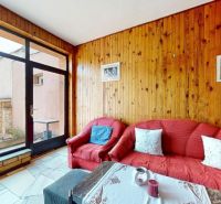 A seating area in a family house with wooden paneling and a view of the yard.
